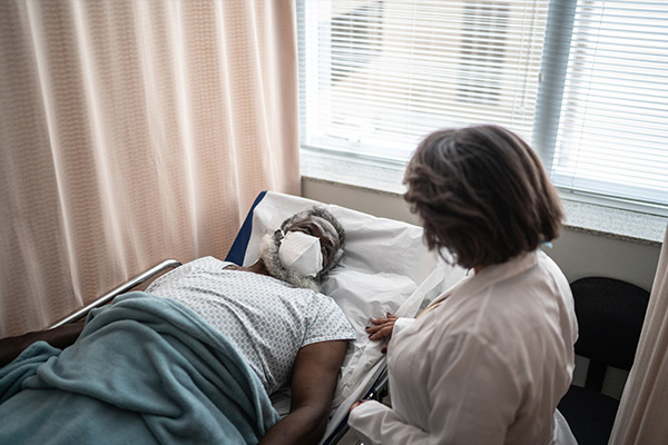 Revolutionizing-post-operative-care image of person in hospital bed with carer