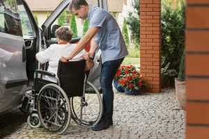 Man helping lady in wheelchair into a car